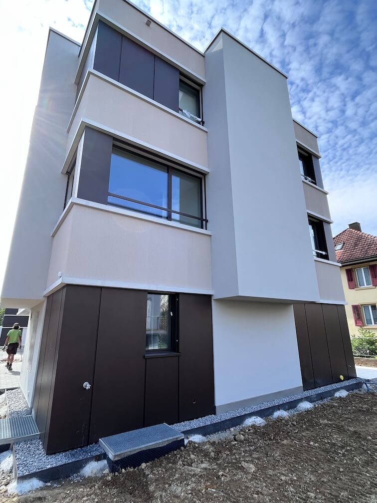 Moderne Fassadengestaltung mit Kombination aus Putz und dunklen Fassadenplatten an einem Mehrfamilienhaus in der Gartenstrasse, 6340 Baar.