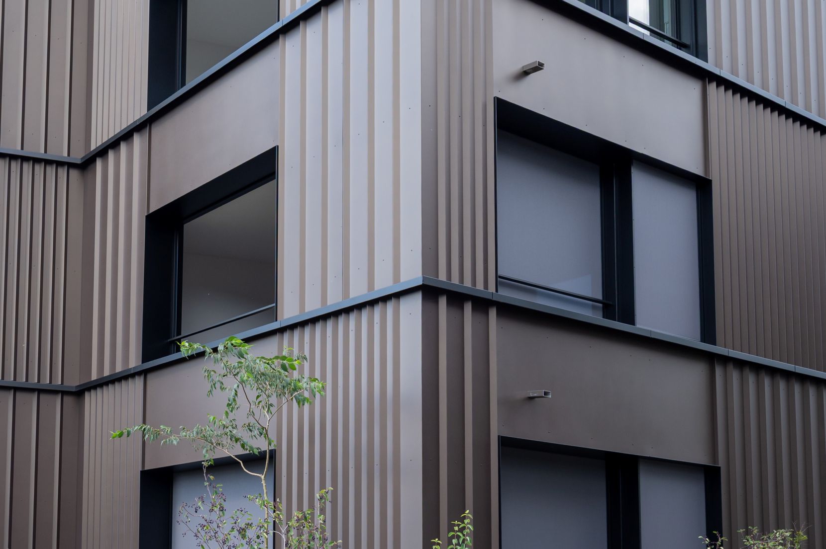 Detailaufnahme der Metallfassade mit vertikaler Fassadenstruktur an der Wohnüberbauung Panoramaweg in Baar.