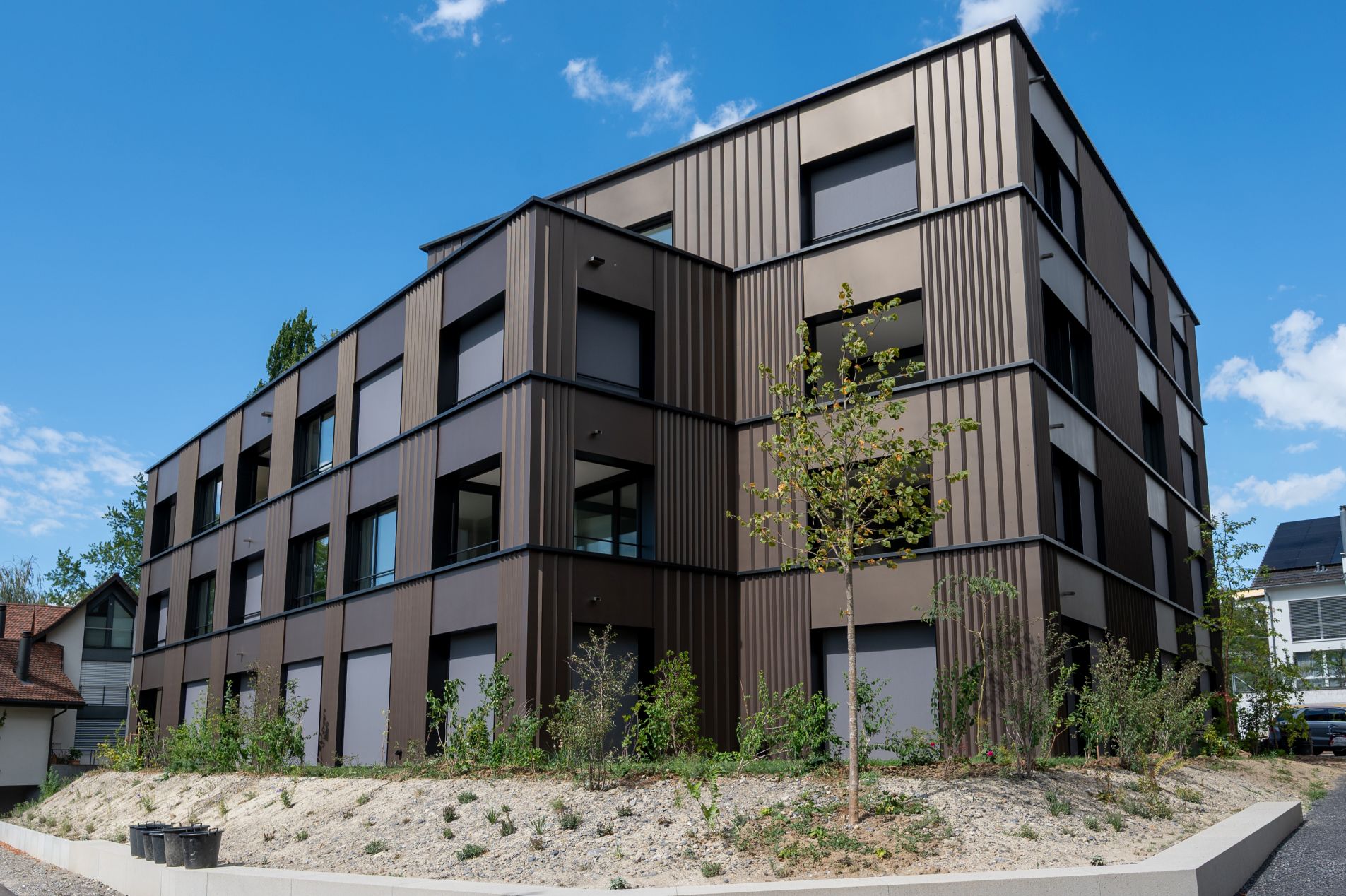 Eckansicht der Wohnüberbauung Panoramaweg in Baar mit vorgehängter hinterlüfteter Fassade und moderner Gebäudehülle.