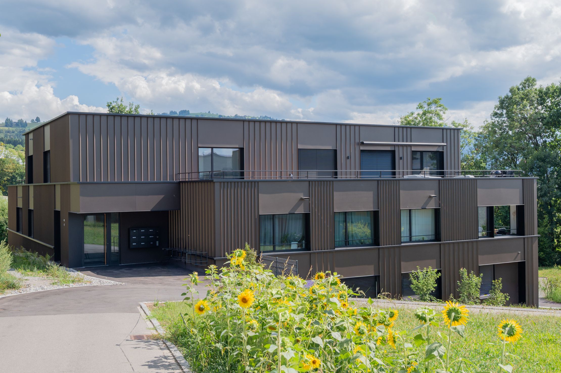 Gesamtansicht der Wohnüberbauung Panoramaweg in Baar mit vorgehängter hinterlüfteter Metallfassade.
